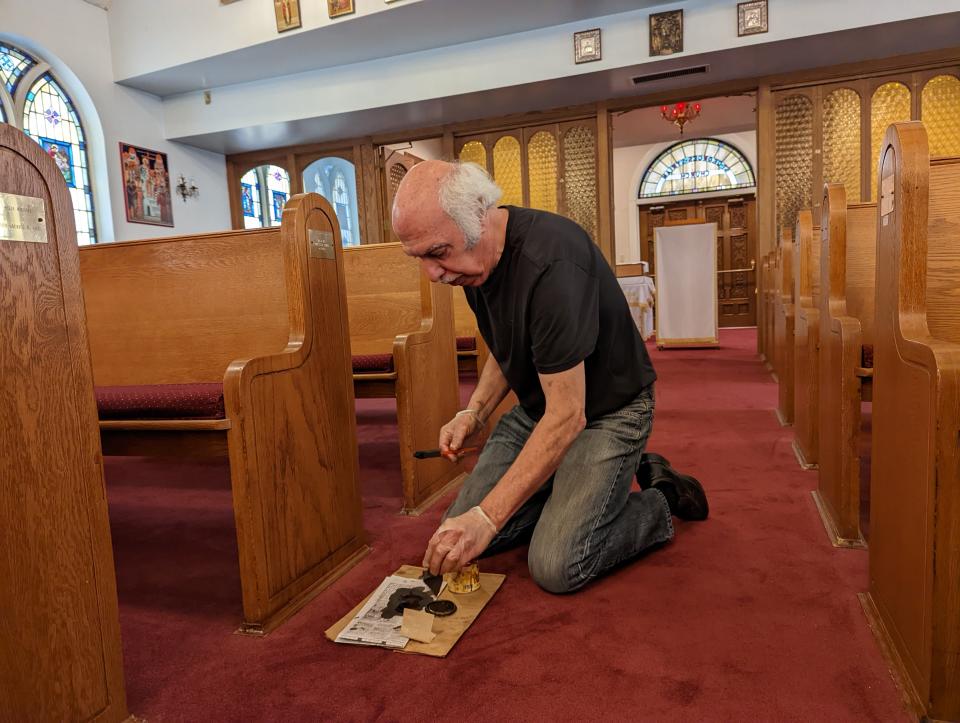 Ed Bendekgey Jr. applies finishing touches to the pews at St. George Antiochian Orthodox Church in Canton, which celebrates its 100th anniversary this weekend.