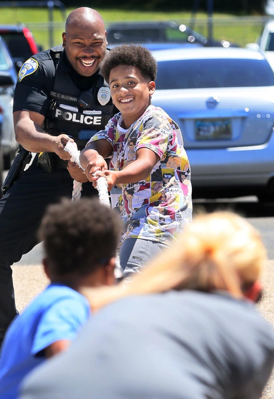 Akron police officer Cameron McGowan joins with De'Angelo Cotto, 11, in a tug of war at the Juneteenth Vax and Vote Blitz at the Akron Urban League in Akron on Friday.