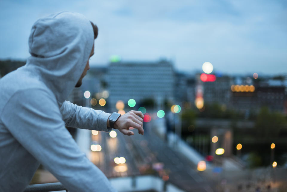 Athlete checking his smartwatch above the city at dawn