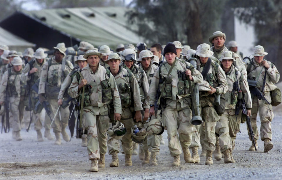 FILE - In this Dec. 31, 2001, file photo, U.S. Marines with full battle gear prepare to leave the U.S. military compound at Kandahar airport for a mission to an undisclosed location. The Marines departed in transport helicopters, their destination classified. Veterans of America's longest war are torn as the U.S. signs a potentially historic peace accord with the Taliban in Afghanistan. For many, the U.S. is overdue in withdrawing its forces after more than 18 years of fighting. Others are wary of the Taliban, whose hard-line government the U.S.-led forces overthrew in 2001. (AP Photo/John Moore, File)