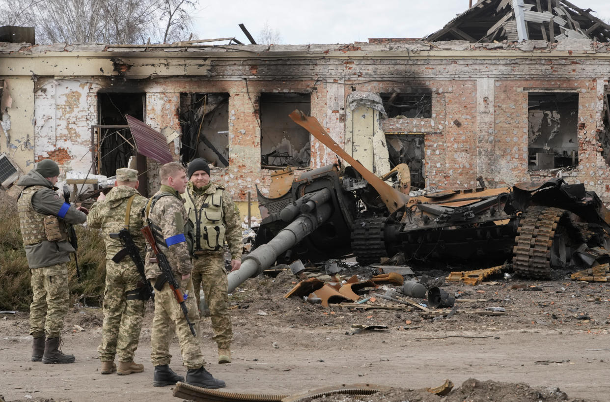 Ukrainian soldiers watch debris from a Russian tank after recent fights in the town of Trostsyanets, some 400km (250 miles) east of capital Kyiv, Ukraine, Monday, March 28, 2022. The more than month-old war has killed thousands and driven more than 10 million Ukrainians from their homes including almost 4 million from their country. (AP Photo/Efrem Lukatsky)