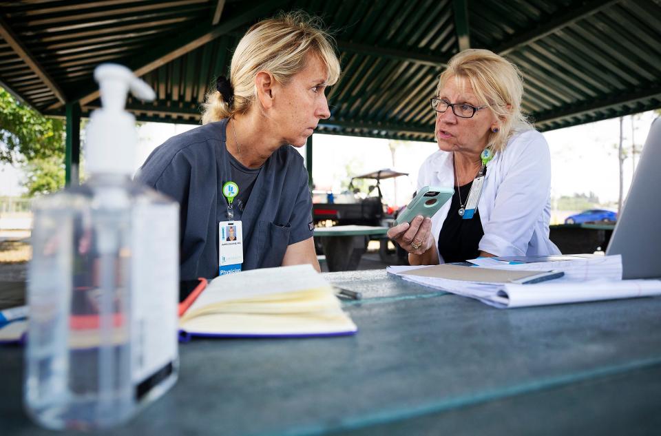Dr. Karen Calkins and Kathy Richards-Bessshare give COVID-19 testing updates on a conference call at a mobile testing site setup in a park in Cape Coral, Fla.