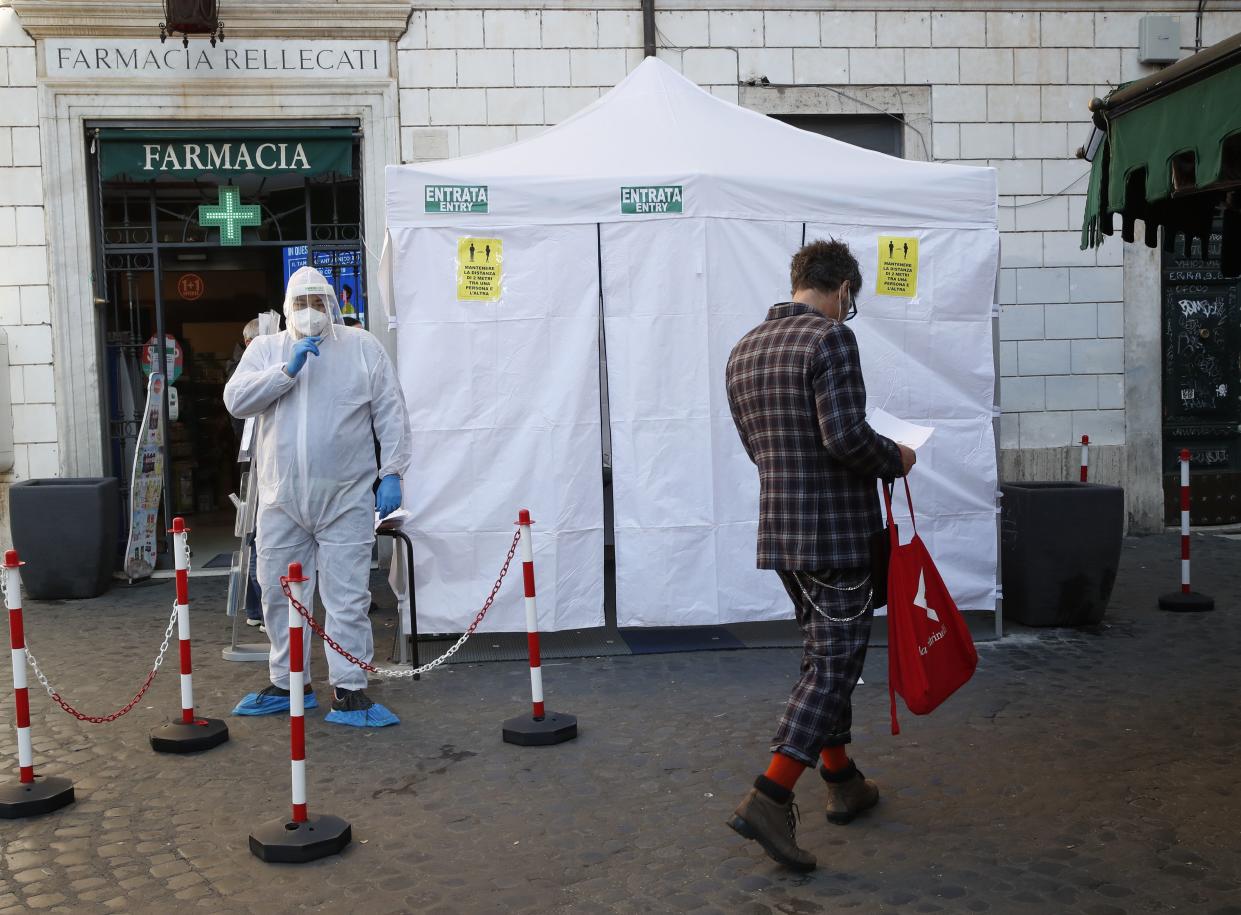 Pharmacy personnel wears protective gear as he stands outside a tent set up for rapid COVID-19 tests in Rome's Trastevere neighborhood on Tuesday, Nov. 24, 2020.