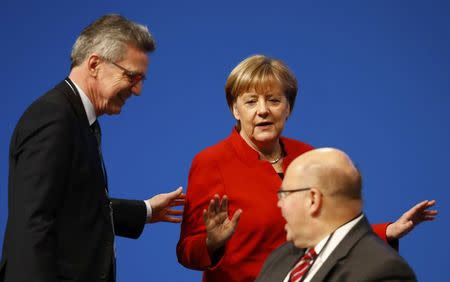 German Chancellor and leader of the conservative Christian Democratic Union party CDU Angela Merkel talks to Interior Minister Thomas de Maiziere (L) and head of the Federal Chancellery Peter Altmeier (R) during the CDU party convention in Essen, Germany, December 6, 2016. REUTERS/Wolfgang Rattay