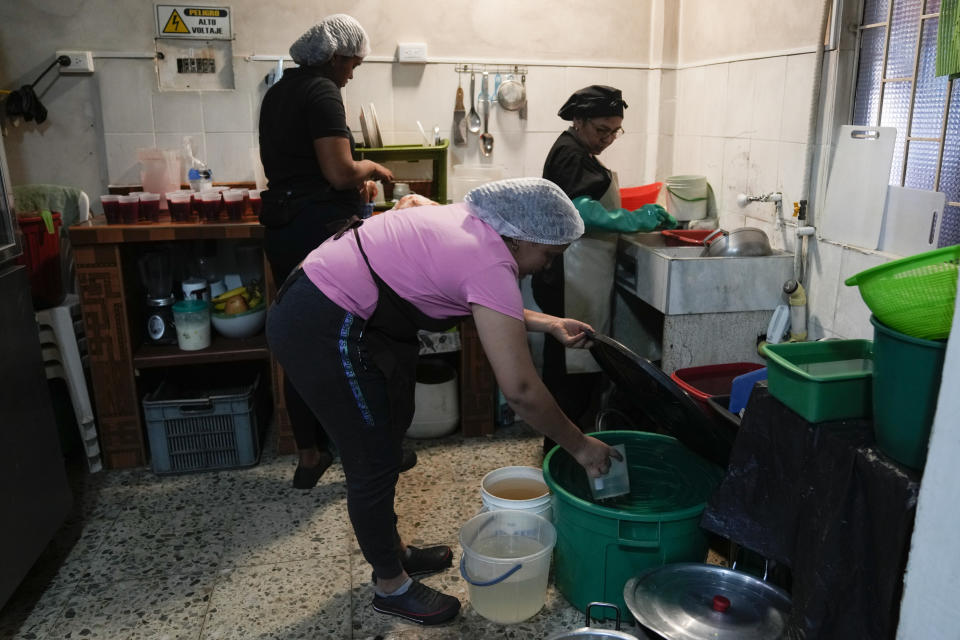A restaurant cook gets water from a bucket while the kitchen stays open during a 24-hour water restriction in Bogota, Colombia, Friday, April 12, 2024. Water rationing in the capital began on Thursday due to the low level of water in reservoirs that give drinking water to the capital, a consequence of the El Niño weather phenomenon. (AP Photo/Fernando Vergara)