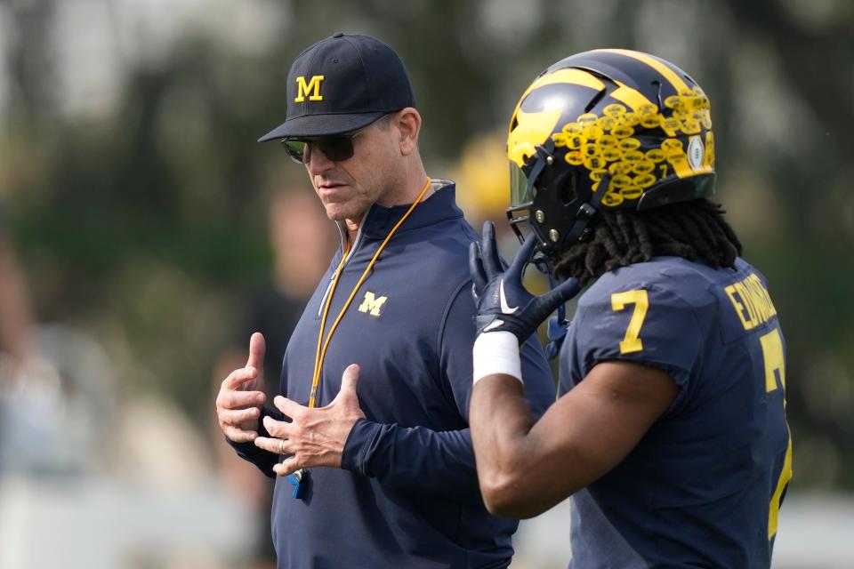 Michigan head coach Jim Harbaugh, left, gestures to running back Donovan Edwards (7) during NCAA college football practice Friday, Dec. 29, 2023, in Carson, Calif. Michigan is scheduled to play against Alabama on New Year's Day in the Rose Bowl, a semifinal in the College Football Playoff.