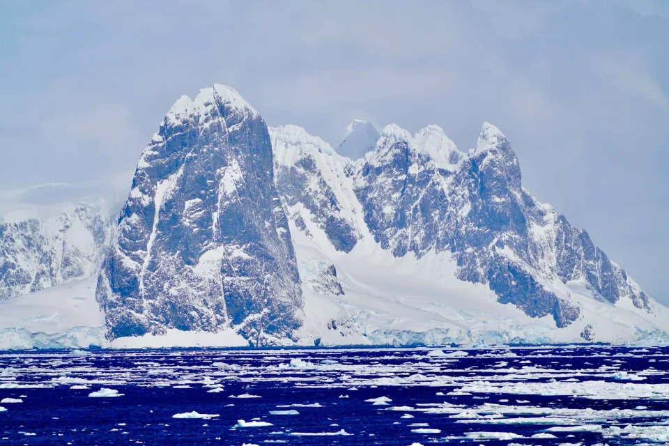 An Antarctic "tidewater" glacier meets the ocean in this 2018 photo that also shows sea ice floating on the water's surface.