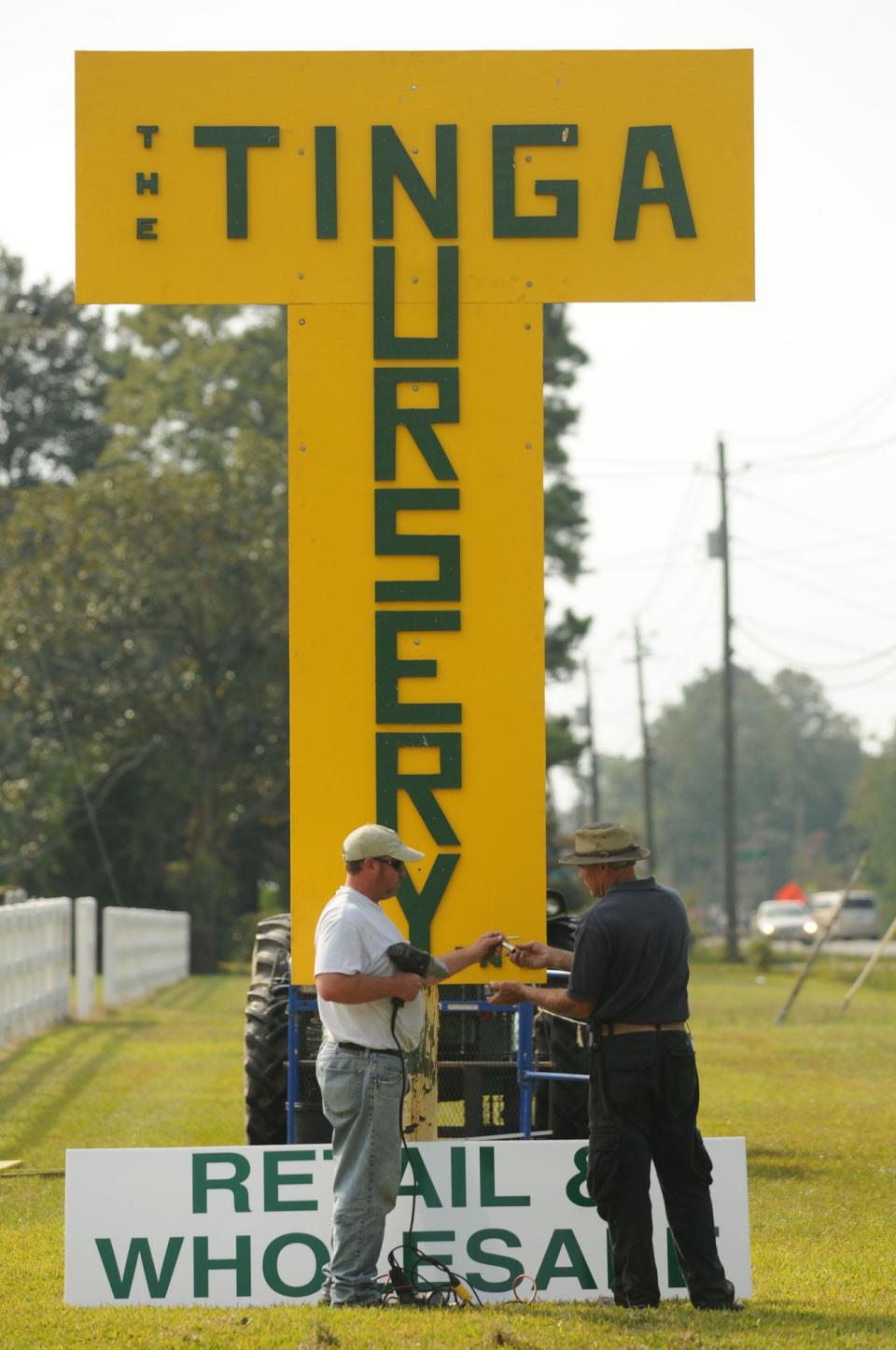 Eelco Tinga, III (left) and his father, Eelco Tinga, Jr. update their sign along Castle Hayne Road in 2010.