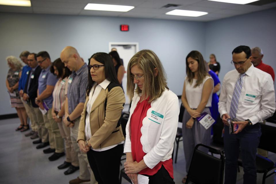 Heather Sanders, foreground, of the U.S. Dept. of Labor - Occupational Safety and Health Administration, bows her head during a moment of silence for those who died in work-related accidents during a memorial ceremony at the Northeast Florida Safety Council in Jacksonville.