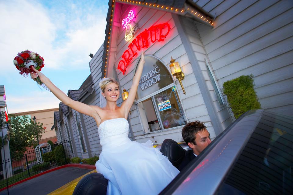 Couple gets married and sit inside convertible outside of wedding chapel.