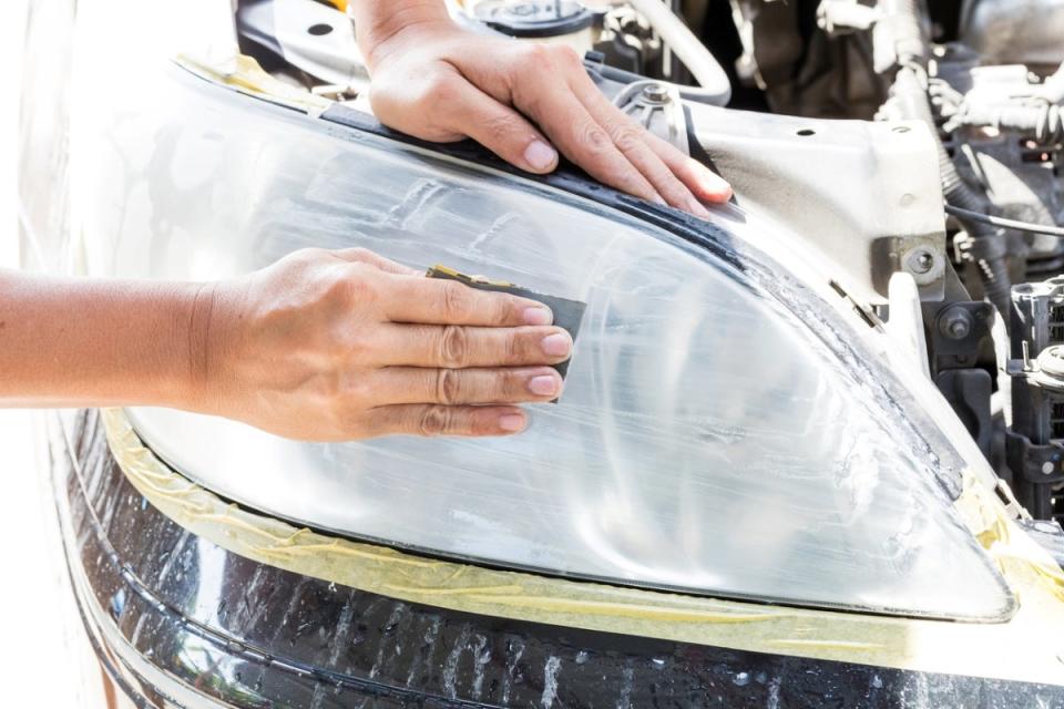 Person rubbing white paste onto car headlight