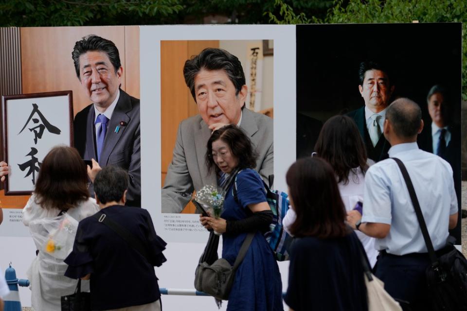 人們在東京增上寺祈禱前，觀看日本前首相安倍晉三的照片。美聯社