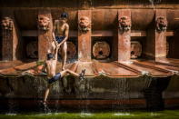 Two boys cool off in a fountain at the India Gate monument in New Delhi, India, as a 40C heatwave swept across the capital.