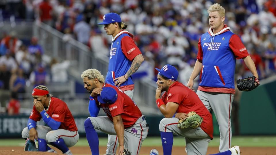 Mar 15, 2023;  Miami, Florida, USA;  Puerto Rico players take a knee as pitcher Edwin Diaz (not pictured) gets checked on by training staff after an apparent leg injury during the team celebration against Dominican Republic at LoanDepot Park.