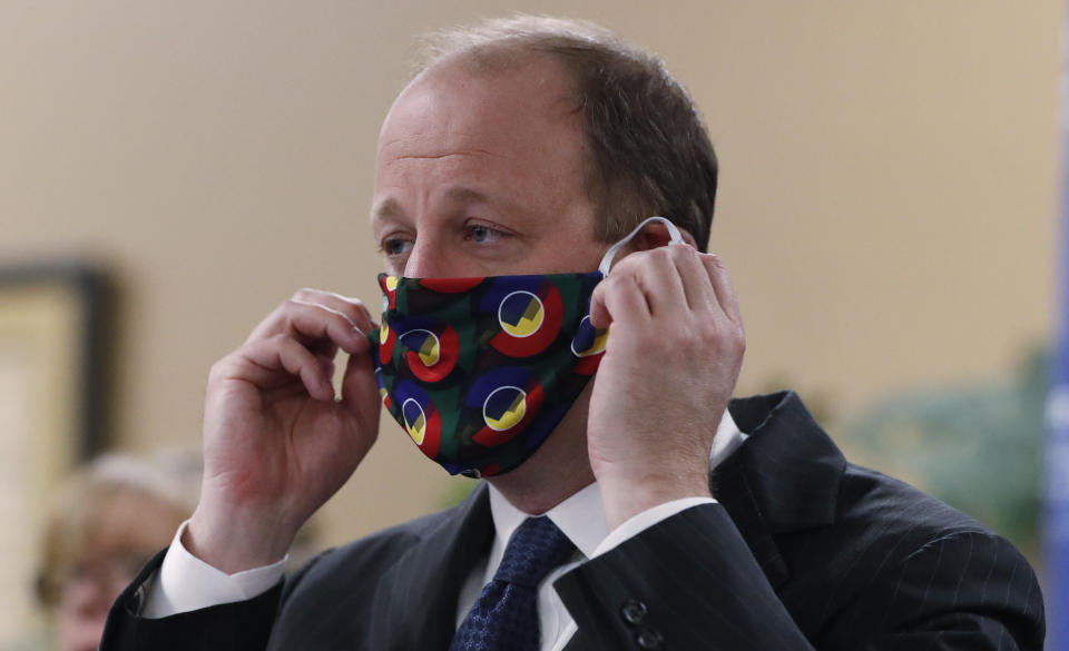 Colorado Gov. Jared Polis dons a mask to encourage state residents to wear them while in public as a statewide stay-at-home order remains in effect in an effort to reduce the spread of the new coronavirus Friday, April 3, 2020, in Centennial, Colo. (AP Photo/David Zalubowski)