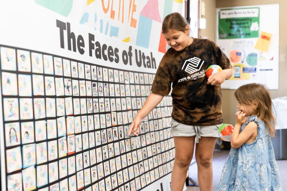 Sofia, left, and Varvara, from Ukraine, point out faces on The Faces of Utah board while their mother picks up supplies at the Serve Refugees Sharehouse in South Salt Lake on Thursday, July 13, 2023. The board will go to the governor’s office to show the diversity of people who live in Utah. | Megan Nielsen, Deseret News