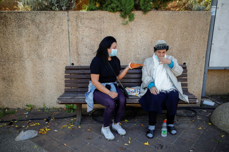 A woman holds a slice of pizza, which was handed to her after she was vaccinated against the coronavirus disease (COVID-19) as part of an initiative to encourage people to get vaccinated, near a temporary vaccination centre in Tel Aviv