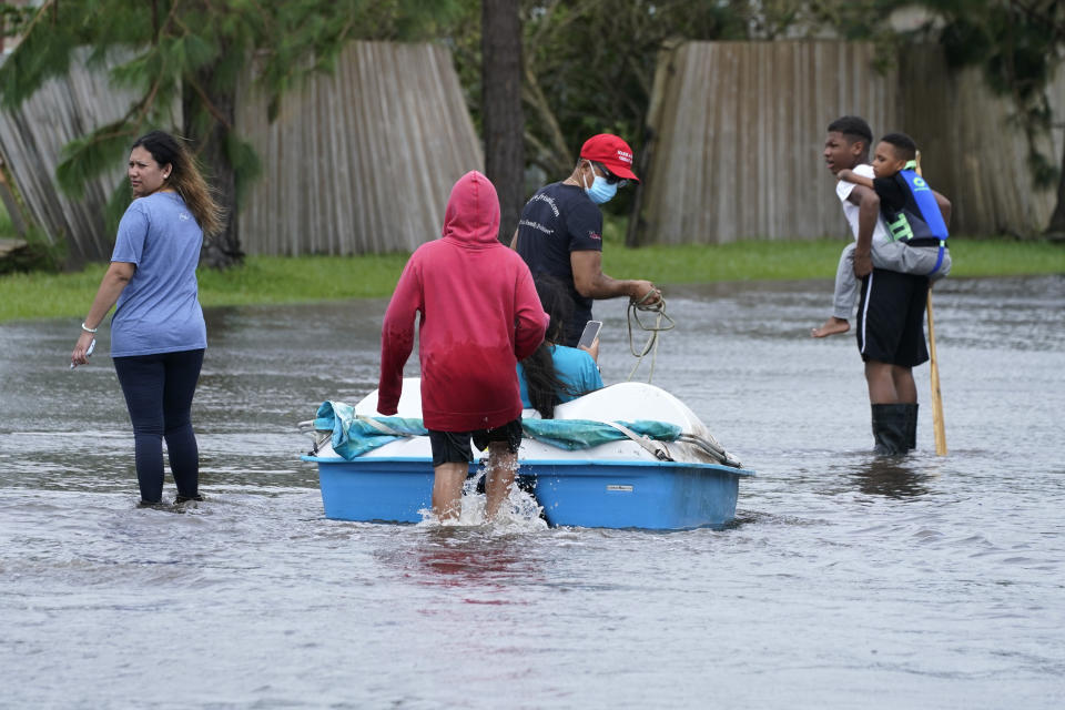 Residents walk a boat back into a flooded neighborhood to retrieve belongings after Hurricane Ida moved through Monday, Aug. 30, 2021, in LaPlace, La. (AP Photo/Steve Helber)