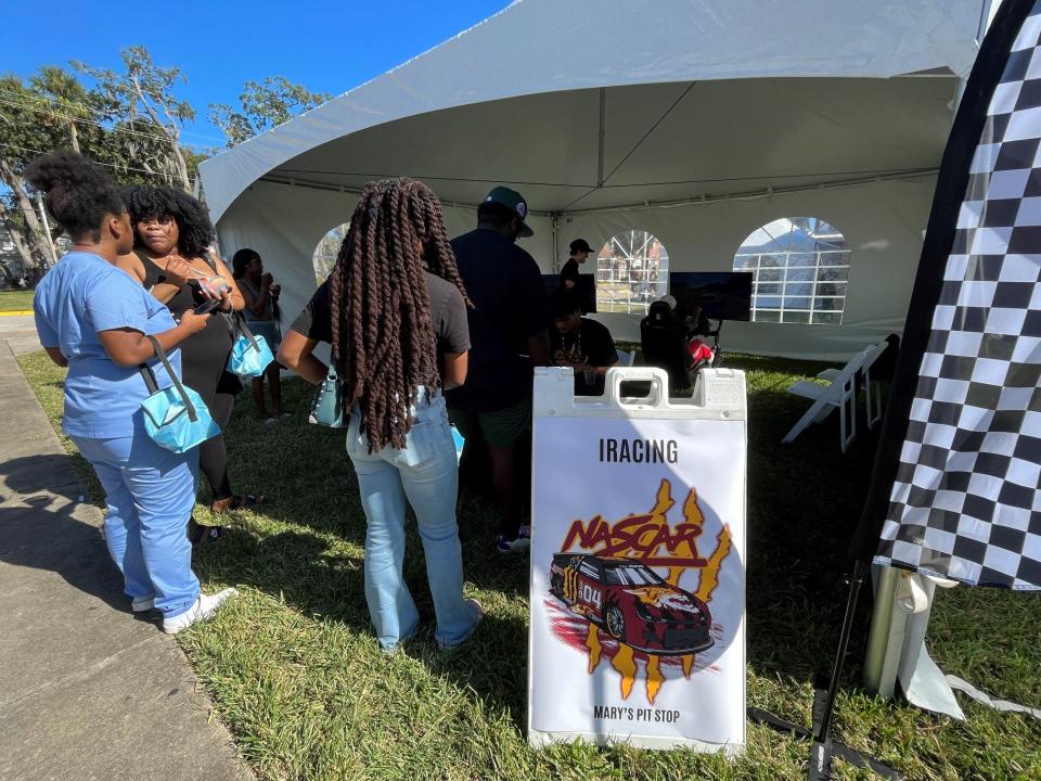 Bethune-Cookman University students involved with the NASCAR Campus Lab program pose behind a specially wrapped race car that was displayed on the Daytona Beach campus on Oct. 27.