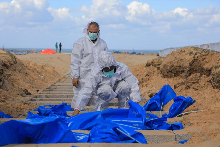 Trabajadores palestinos entierran un cuerpo en una tumba para las víctimas muertas en el conflicto, en la ciudad de Rafah, en el sur de la Franja de Gaza, el 30 de enero de 2024.