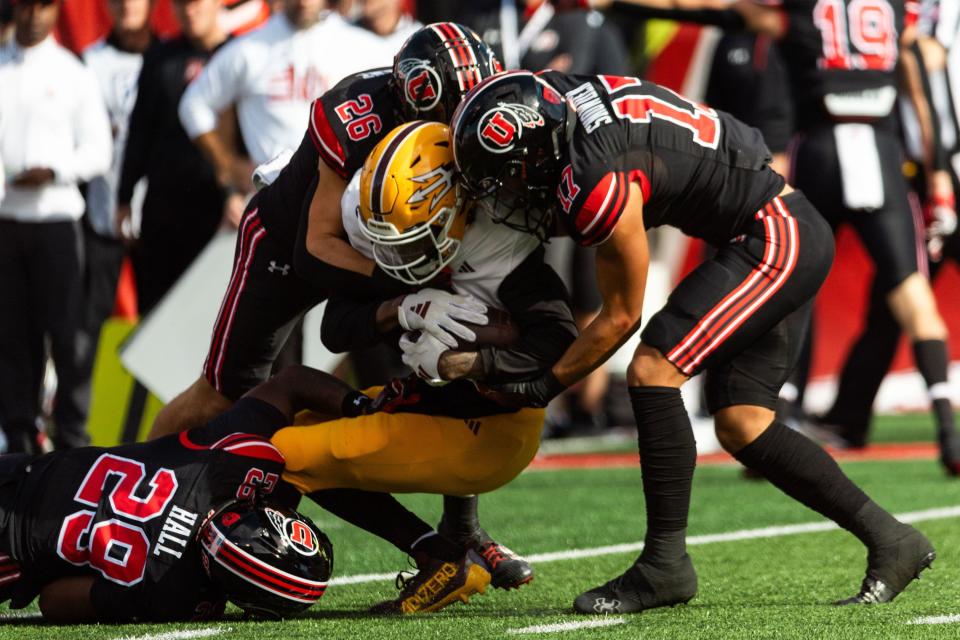 Arizona State Sun Devils wide receiver Elijhah Badger is tackled by Utah’s Johnathan Hall, left, Charlie Vincent and Smith Snowden, right, wearing black.