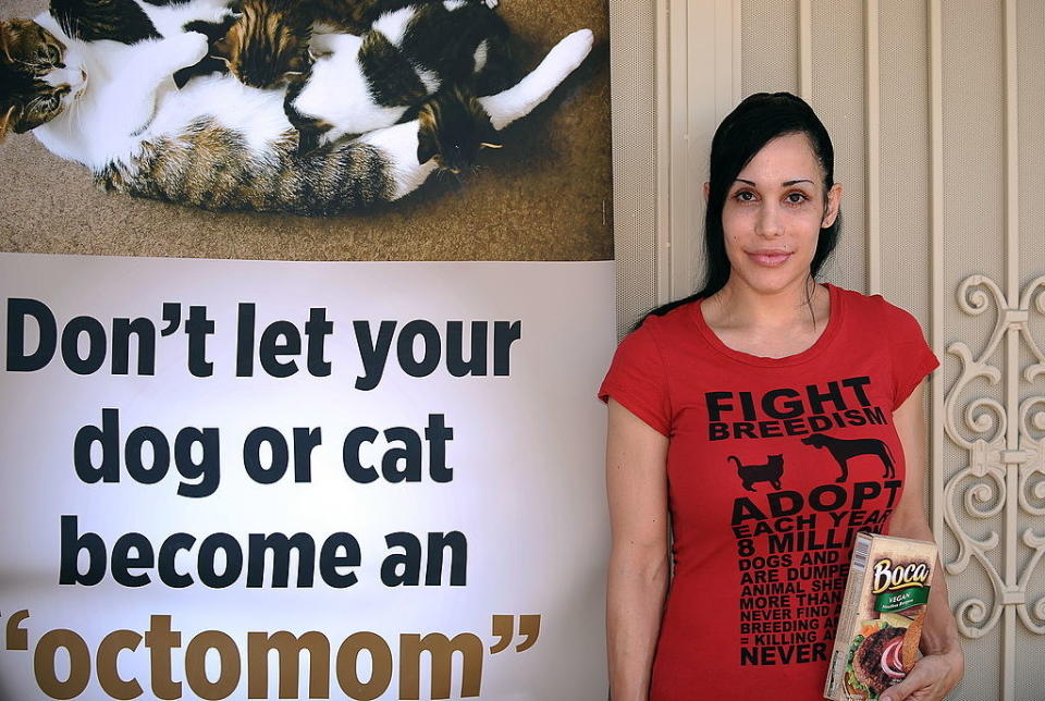 Nadya standing next to a sign showing a cat with kittens and the caption "Don't let your dog or cat become an 'octomom'"