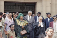 <p>Winnie Mandela, left, wife of African National Congress leader Nelson Mandela, center right, leaves the Rand Supreme Court on Feb. 13, 1991, after an adjournment after two key state witnesses, fearing for their safety, refused to testify in the case in which Mrs. Mandela is charged with kidnapping and assault. (Photo: AP) </p>