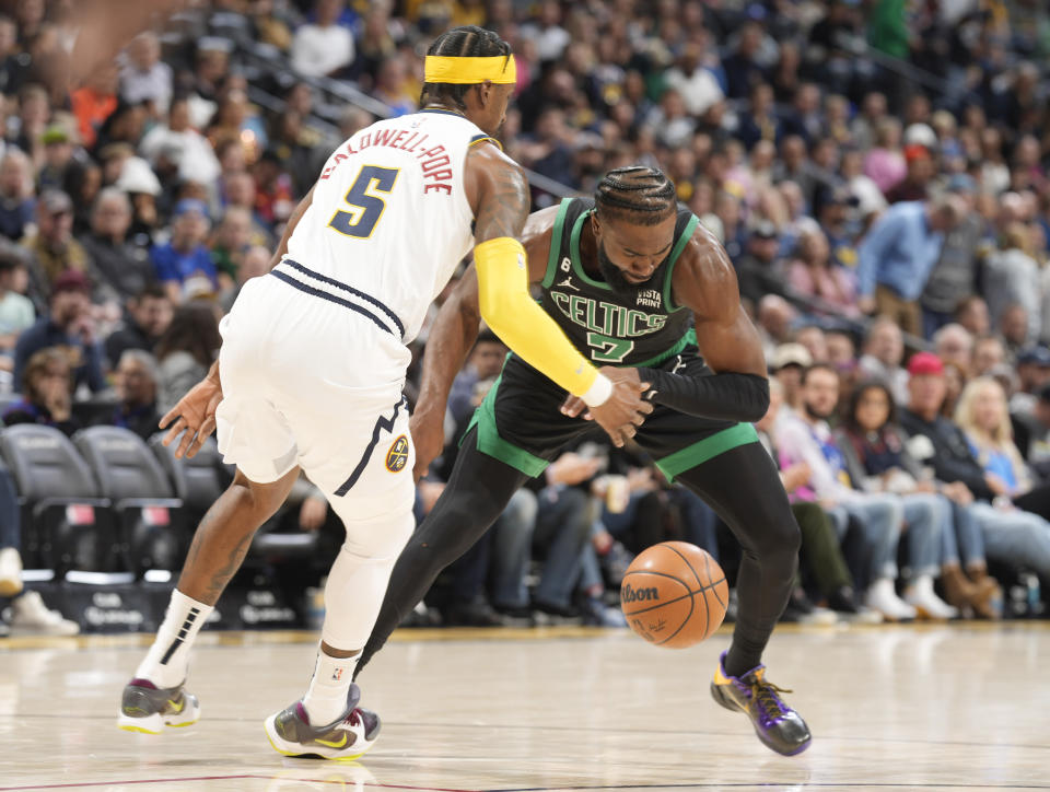 Boston Celtics guard Jaylen Brown, right, fights for control of a loose ball with Denver Nuggets guard Kentavious Caldwell-Pope in the first half of an NBA basketball game, Sunday, Jan. 1, 2023, in Denver. (AP Photo/David Zalubowski)