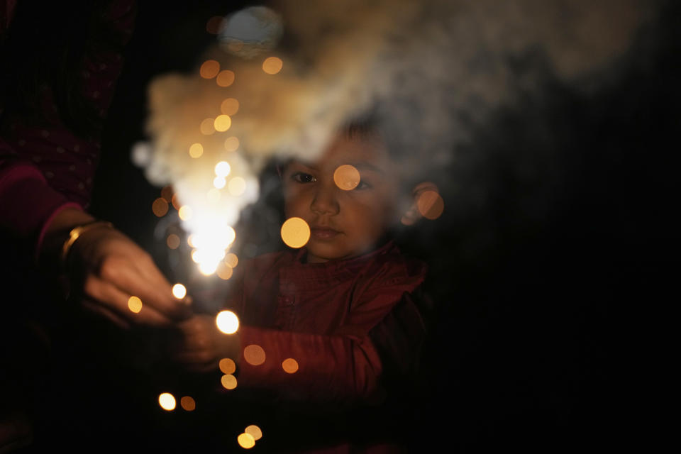 Pathik Bhalodiya, 4, gets help from his mother Shital, members of an Indian family living in Japan, to hold a piece of firework as they celebrate Diwali, the Hindu festival of lights, at a park in Tokyo, Thursday, Nov. 4, 2021. Millions of people across Asia are celebrating the Hindu festival of Diwali, which symbolizes new beginnings and the triumph of good over evil and light over darkness. The festival is celebrated mainly in India but Hindus across the world, particularly in other parts of Asia, also gather with family members and friends to socialize, visit temples and decorate houses with small oil lamps made from clay. (AP Photo/Hiro Komae)