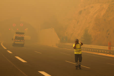 A volunteer directs vehicles as a wildfire burns in Kineta, near Athens, Greece, July 23, 2018. REUTERS/Alkis Konstantinidis