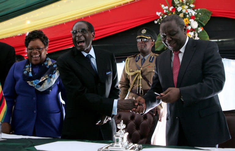 Zimbabwe's President Robert Mugabe (C) laughs as he shakes hands with Prime Minister Morgan Tsvangirai (R) and Vice President Joice Mujuru (L) after signing Zimbabwe's new constitution at the State House in Harare on May 22, 2013