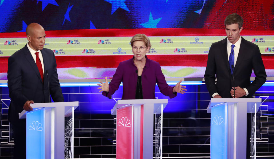 Democratic presidential candidate Sen. Elizabeth Warren, D-Mass, speaks at the Democratic primary debate hosted by NBC News at the Adrienne Arsht Center for the Performing Arts, Wednesday, June 26, 2019, in Miami, as Sen. Cory Booker, D-N.J., left and former Texas Rep. Beto O'Rourke listen. (AP Photo/Wilfredo Lee)