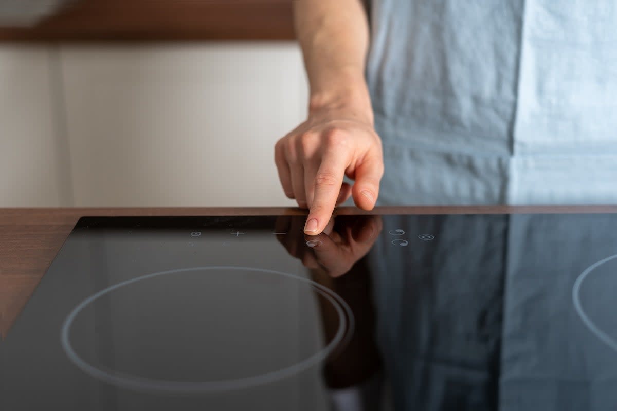 A person turning on an induction stove.