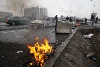 FILE - People walk past cars, which were burned after clashes, on a street in Almaty, Kazakhstan, Friday, Jan. 7, 2022. On Jan. 2, small protests broke out in an oil city in western Kazakhstan where residents were unhappy about a sudden spike in prices for liquified gas, which is widely used as automotive fuel. By Jan. 5, the protests descended into violence, with armed groups storming government buildings and setting cars and buses on fire in Kazakhstan's largest city, Almaty. (AP Photo/Vasily Krestyaninov, File)