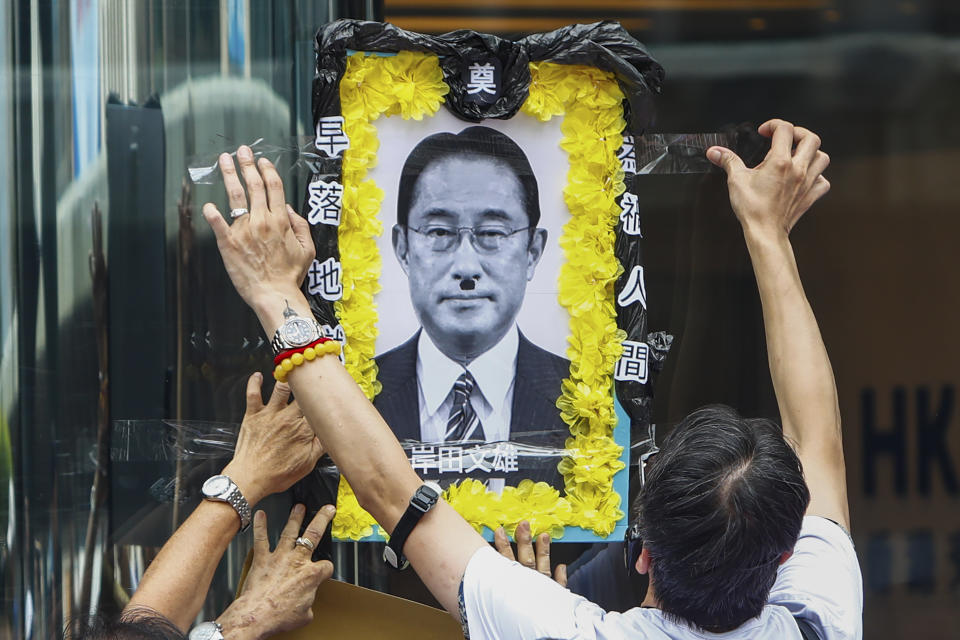 People stick a depiction of a funeral portrait of Japanese Prime Minister Fumio Kishida onto a glass wall during a protest against the discharge of treated Fukushima radioactive wastewater, outside the Japan general-consulate in Hong Kong, on Thursday, Aug. 24, 2023. The Hong Kong authorities have imposed a ban on imports of Japanese seafood as a gesture to oppose Japan's decision to discharge the treated radioactive water from the wrecked Fukushima nuclear power plant. (AP Photo/Daniel Ceng)