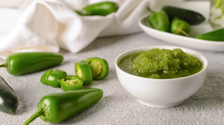 Salsa verde in white bowl with green peppers