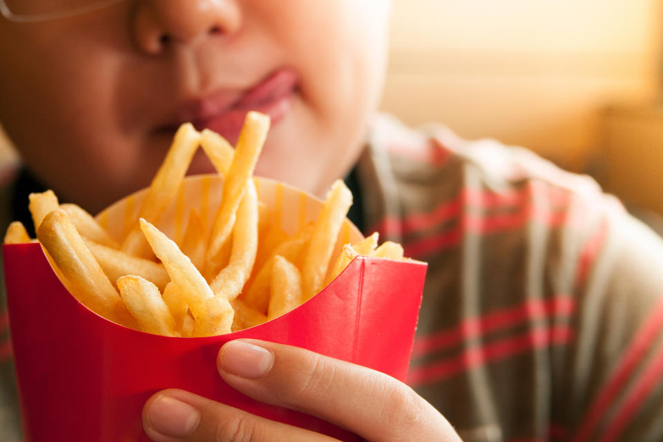 Cropped Image Of Tempted Boy Holding French Fries Packet