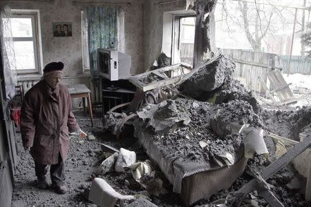 A woman surveys damage done to a house, which according to locals was recently damaged by shelling, in the suburbs of Donetsk January 30, 2015. REUTERS/Alexander Ermochenko
