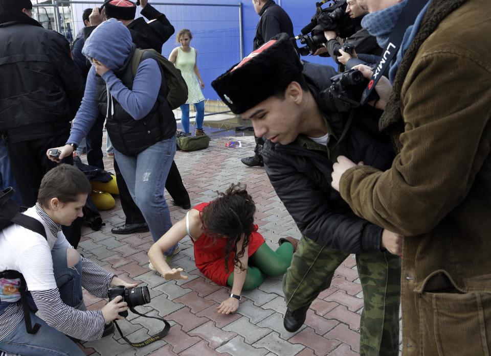 A member of the punk group Pussy Riot lies on the ground as the group are attacked by Cossack militia in Sochi, Russia, on Wednesday, Feb. 19, 2014. The group had gathered to perform in a downtown Sochi restaurant, about 30km (21miles) from where the Winter Olympics are being held.They left the restaurant wearing bright dresses and ski masks and had only been performing for a few seconds when they were set upon by Cossacks. (AP Photo/Morry Gash)