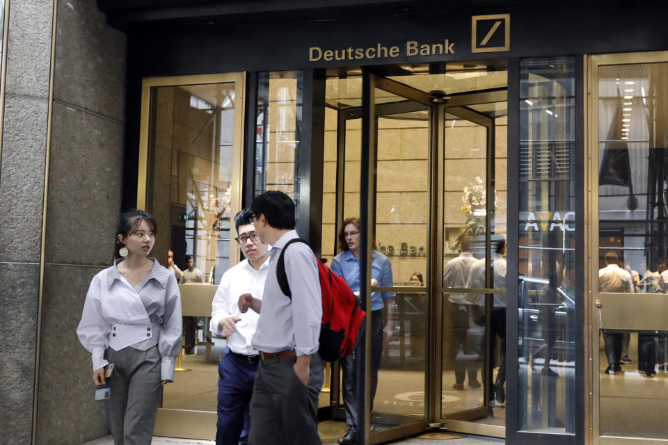 People leave Deutsche Bank in New York, Monday, July 8, 2019. Germany's struggling Deutsche Bank said Sunday it would cut 18,000 jobs by 2022, downsizing its volatile investment banking division in a restructuring aimed at restoring consistent profitability and better returns to shareholders. (AP Photo/Richard Drew)