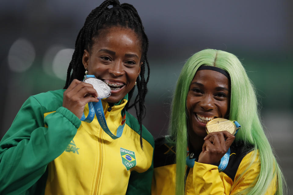 Silver medalist Vitoria Cristina Silva of Brazil, left, and gold medalist Shelly-Ann Fraser-Pryce of Jamaica celebrate at the podium for the women's 200m during the athletics at the Pan American Games in Lima, Peru, Friday, Aug. 9, 2019. (AP Photo/Moises Castillo)