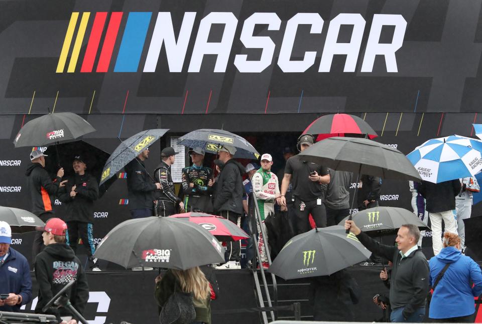 Xfinity drivers wait under umbrellas backstage before driver introductions for the start the United Rentals 300 on Saturday at Daytona International Speedway. That race and the Daytona 500 were postponed until Monday.