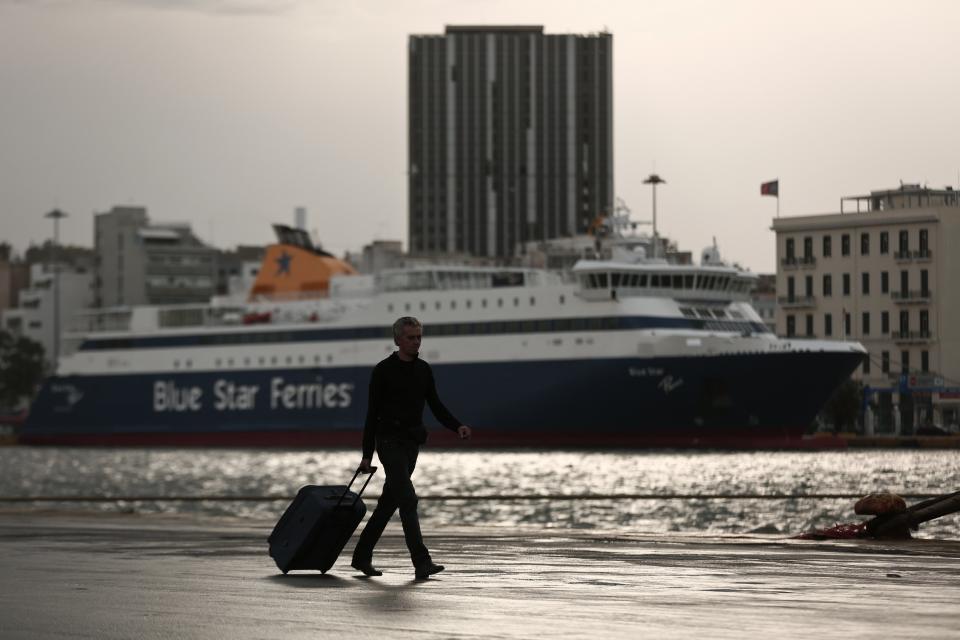 A passenger walks on a promenade during a 24-hour general labour strike at the port of Piraeus near Athens