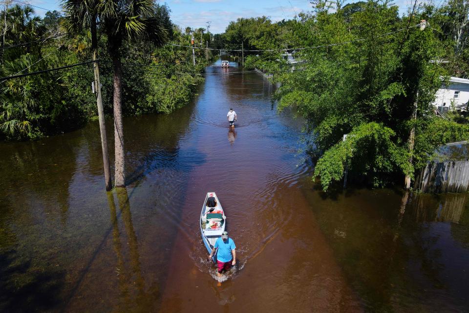 A man pulls a canoe through floodwaters in New Smyrna Beach, just north of Orlando (AFP via Getty Images)