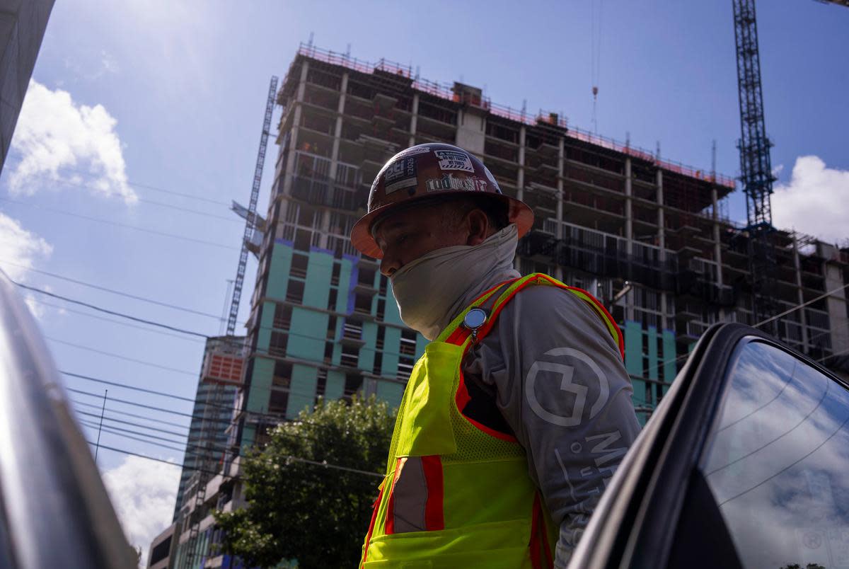 Martin Capallera, 50, a construction employee, throws on his neon vest and slips on his neck gaiter after taking a break in his car while working in the late morning heat in Austin’s West Campus neighborhood on July 6, 2023. Capallera specializes in rewiring buildings and currently works on the 24th floor of a new building on W. 21st Street and San Antonio. “We try to keep our people safe,” Capallera said. “We’re all the time under the sun.”