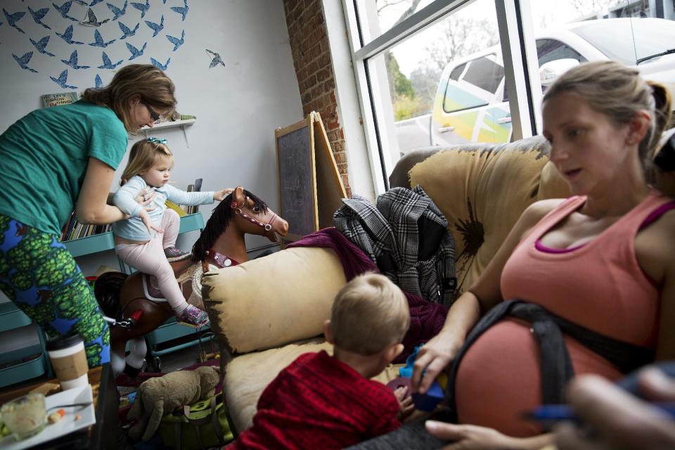 Moira Brennen, 33, left, puts her daughter Audrey, 2, on a rocking horse while meeting at a coffee shop with fellow stay-at-home mother Jessica Greene, 37, and her son, Woods, 2, in East Atlanta, Ga., in Dekalb County, Thursday, Jan. 5, 2017. Brennen voted for Clinton and is fearful of a Donald Trump presidency, but doesn't necessarily think it will directly impact her negatively. Her standard for him at this point, is for him to avoid war. (AP Photo/David Goldman)