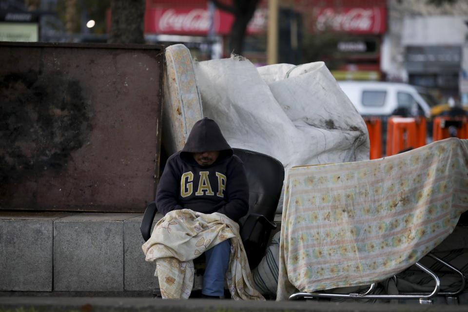 A homeless man sits in a public square in Buenos Aires, Argentina, Wednesday, April 15, 2020, amid a lockdown to help contain the spread of the new coronavirus. (AP Photo/Natacha Pisarenko)