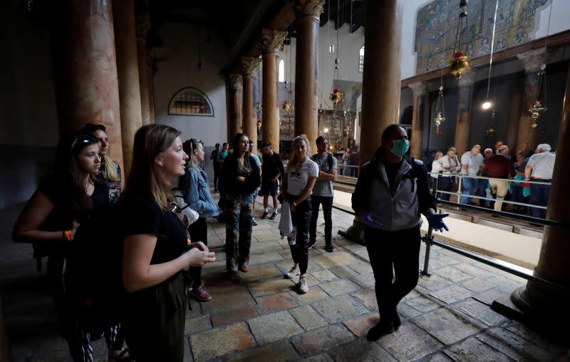 A tourist wearing a mask as a preventive measure against the coronavirus gestures as she visits the Church of the Nativity in Bethlehem in the Israeli-occupied West Bank