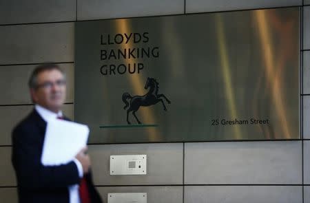 A man waits outside the corporate headquarters of Lloyds Banking Group in the City of London August 1, 2013. REUTERS/Andrew Winning