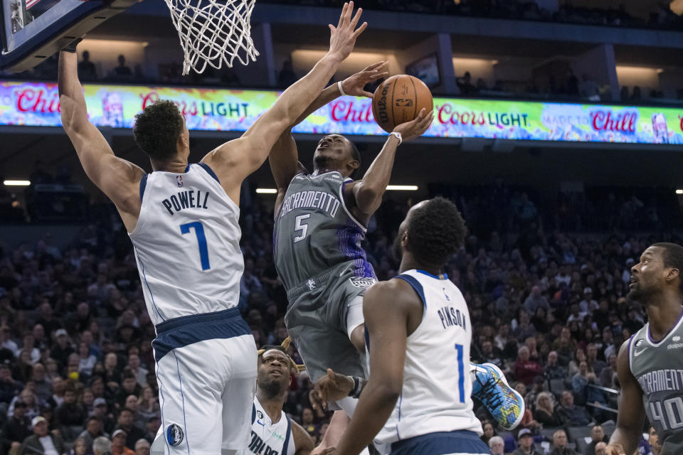 Sacramento Kings guard De'Aaron Fox (5) drives to the basket as Dallas Mavericks center Dwight Powell (7) defends during the second half of an NBA basketball game in Sacramento, Calif., Friday, Feb. 10, 2023. The Mavericks won 122-114. (AP Photo/Randall Benton)